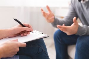 Psychotherapist writing notes, giving diagnosis to emotional man